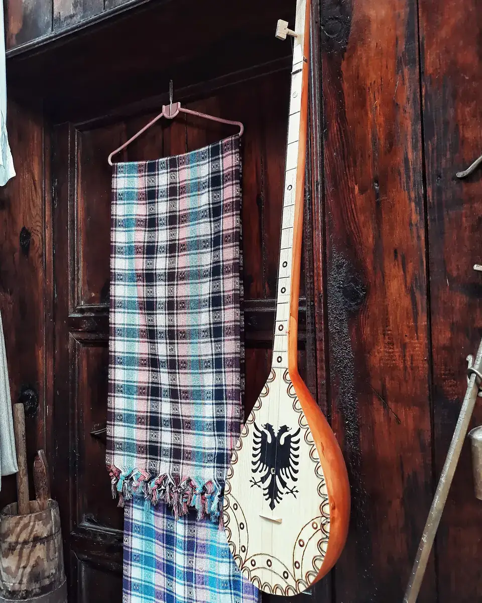A çifteli, the two-stringed Albanian folk instrument, beside a woven textile